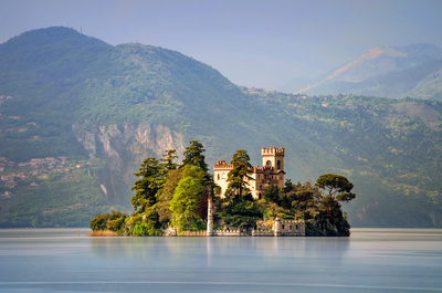 Little island Isola di Loreto on Iseo Lake with mountains in background, Italy 